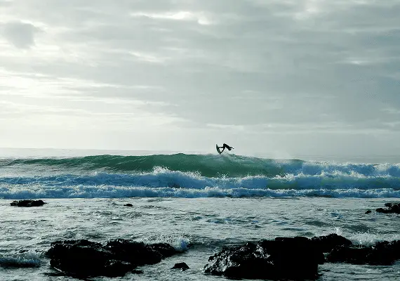Surfeur réalisant une figure aérienne au-dessus d'une vague puissante dans une crique sauvage de Dakhla.