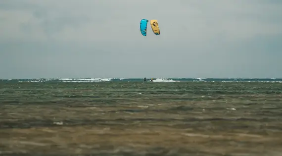 Deux kitesurfeurs naviguant en duo sur les eaux turquoises de la lagune de Dakhla sous un ciel clair.