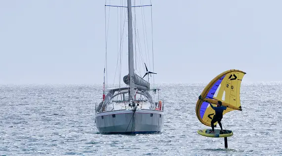 Wingfoileur en navigation à côté d'un voilier sur la lagune de Dakhla.